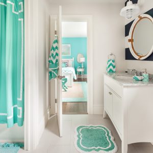 A bright bathroom with a nautical theme features a white gooseneck wall light above a vanity and mirror