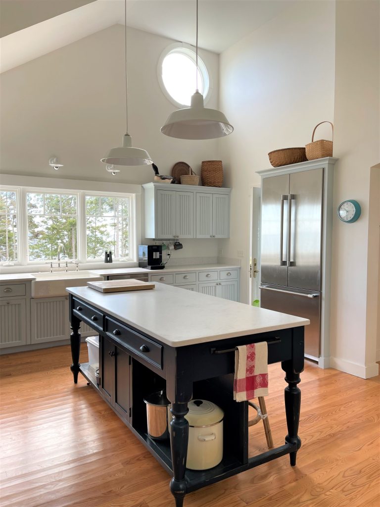Two white pendant lights hang in a spacious kitchen with a large island