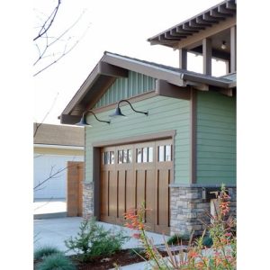 Two gooseneck wall lights are mounted on the exterior of a garage with a wooden door