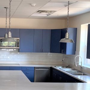 Two industrial-style pendant lights hang above a modern kitchen island with blue cabinetry