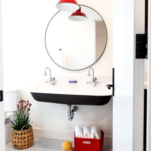 Two red chain-hung pendant lights hang above a black and white double sink in a modern bathroom