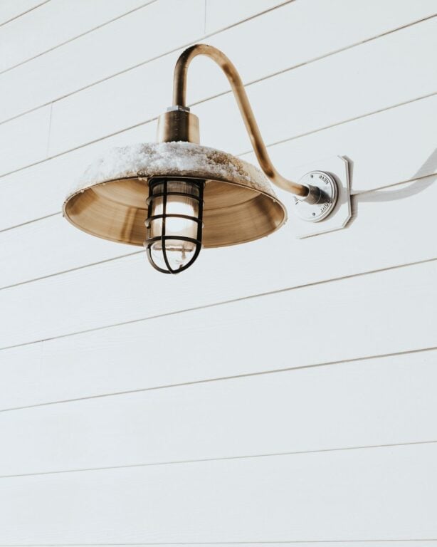 Original Gooseneck Barn Light in Weathered Brass on a White Slatted Exterior
