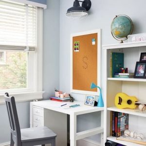A modern industrial-style wall light illuminates a child's study area with a desk and bookshelf