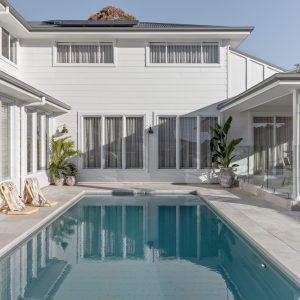 A modern Australian home features a swimming pool and outdoor entertaining area with wall-mounted lights