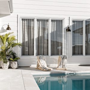Two black wall lights illuminate a modern outdoor patio area next to a swimming pool