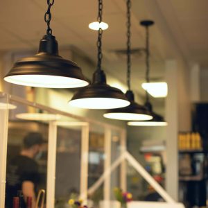 A row of black chain-hung pendant lights illuminate a counter in a restaurant