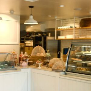 Two white pendant lights illuminate a cafe counter displaying pastries and coffee