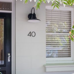 A black gooseneck wall light is mounted next to the number 40 on a light-coloured facade