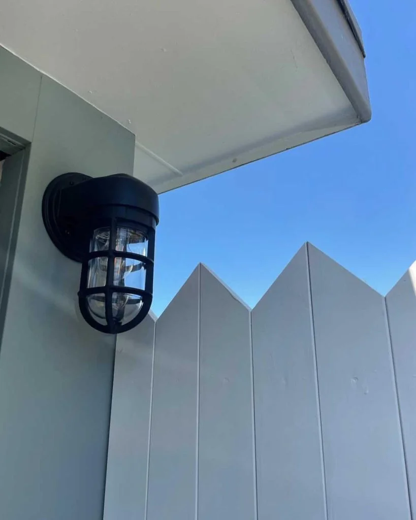 Black Industrial Wall Light on White Picket Fence