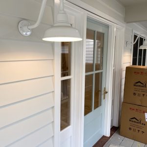 A white gooseneck wall light illuminates the entrance of a home