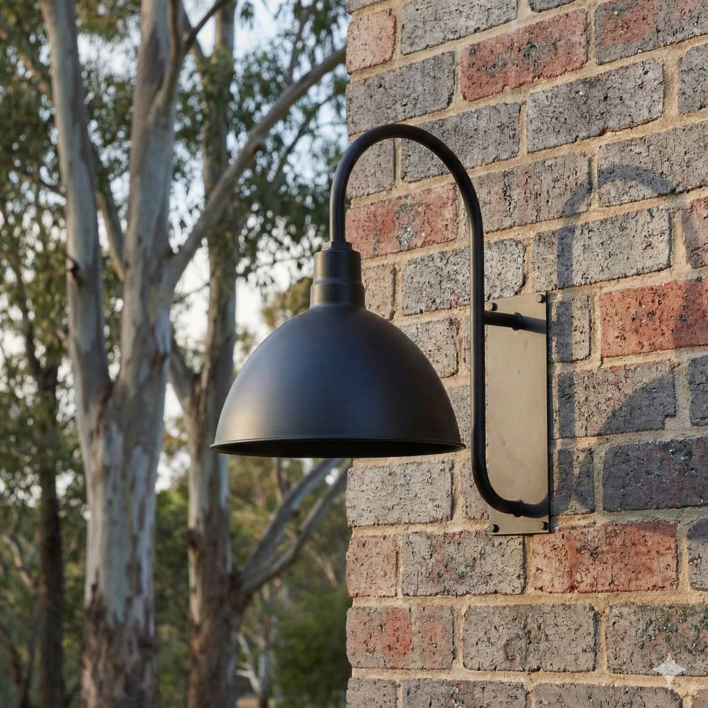 A black gooseneck wall light is mounted on a brick wall with trees in the background