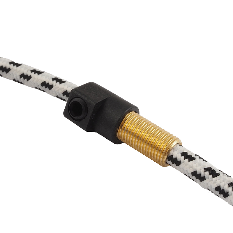 A close-up shot of a black connector with a brass fitting on a black and white patterned cord
