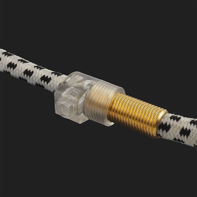 A close-up shot shows a clear plastic and brass fitting connecting two sections of a black and white patterned cord