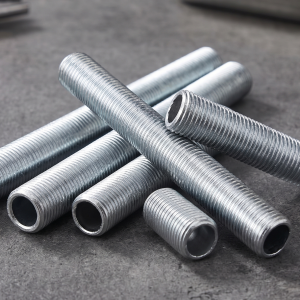 A collection of threaded metal pipes are arranged on a textured grey surface