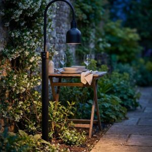 The Cafe Outdoor Post Mount in 17 cm glowing over a garden dining area at dusk - artificially generated scene, reviewed and approved by Jesse Stringer
