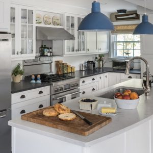 A bright and airy kitchen features blue pendant lights hanging over a kitchen island