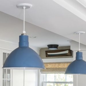Two blue barn-style pendant lights hang from a white ceiling in a bright, modern kitchen